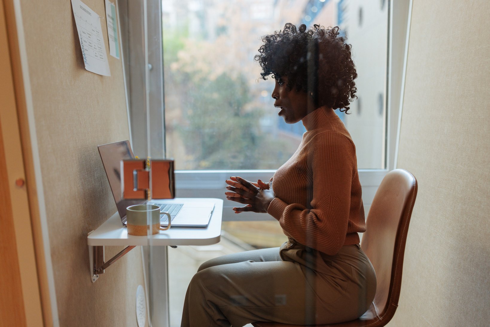 African American businesswoman in zoom meeting in booth at office.